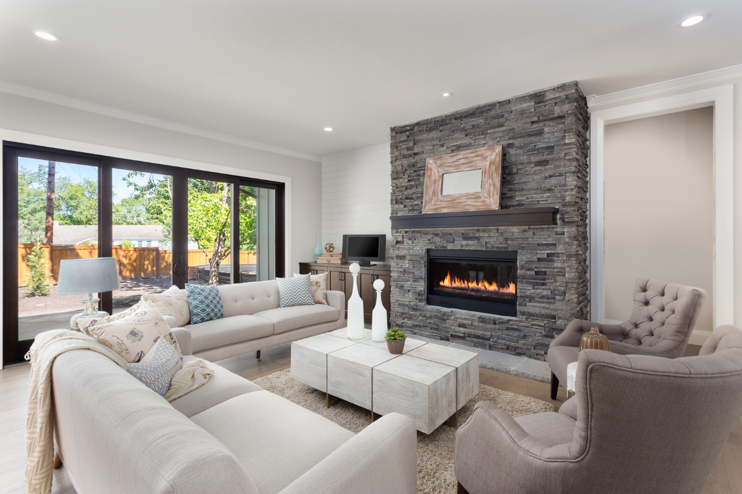 pamela-sandall-design-santa-monica-ca-interior-design-faq-answers-living-room-with-stone-fireplace-sofa-and-chairs-with-large-window-transitional-new-construction